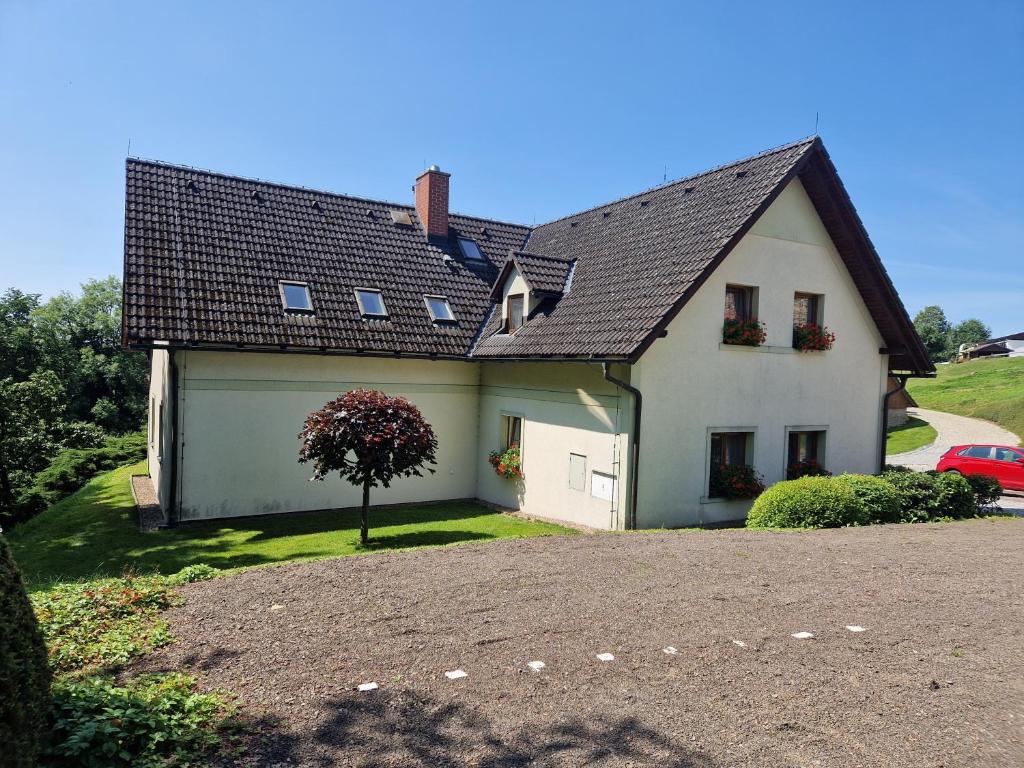 a white house with a tree in front of it at Selský dvůr 2 in Police nad Metují