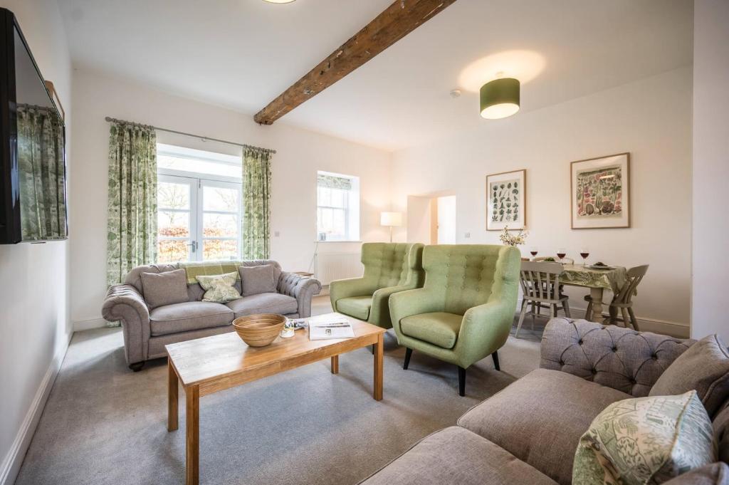 a living room with couches and a table at Ploughman’s Green, Blythburgh in Halesworth