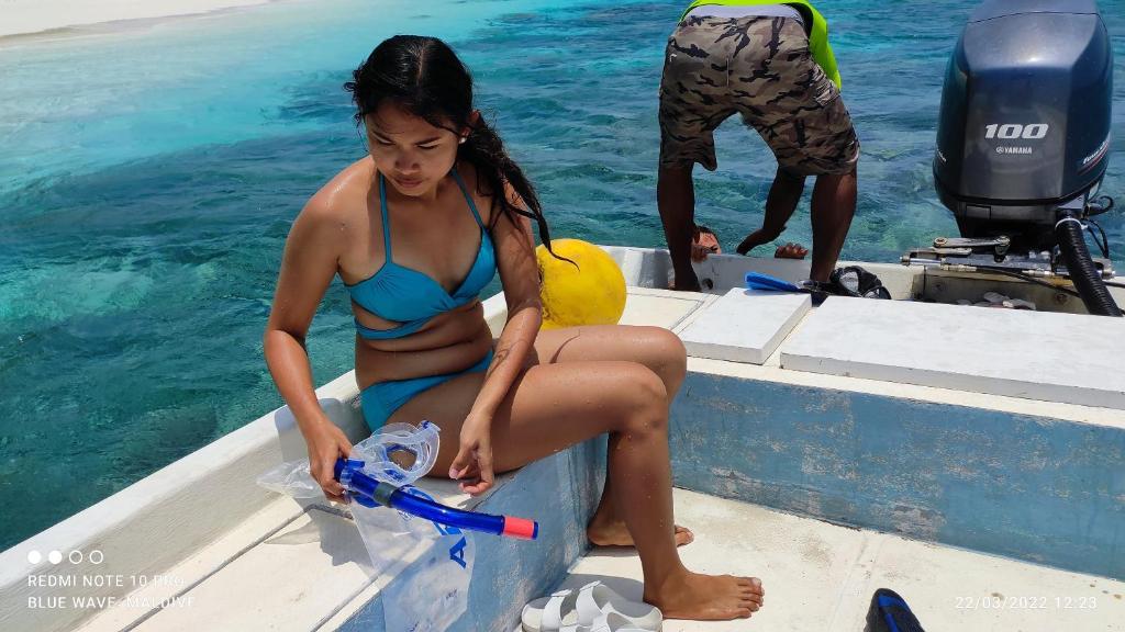 a woman in a blue bikini sitting on a boat at Blue Wave Guesthouse Maldives - Book FB a week gets a free excursion in Kudahuvadhoo