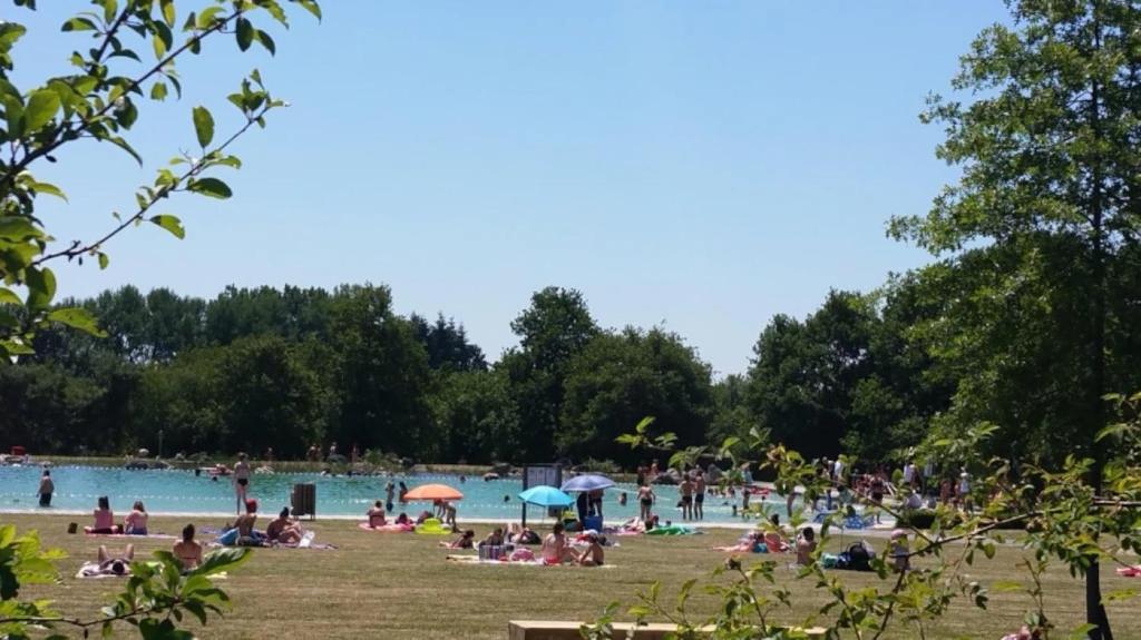 a group of people sitting in the grass by a pool at ZEcamping 3 étoiles animaux acceptés sauna piscine couverte in Mont-près-Chambord
