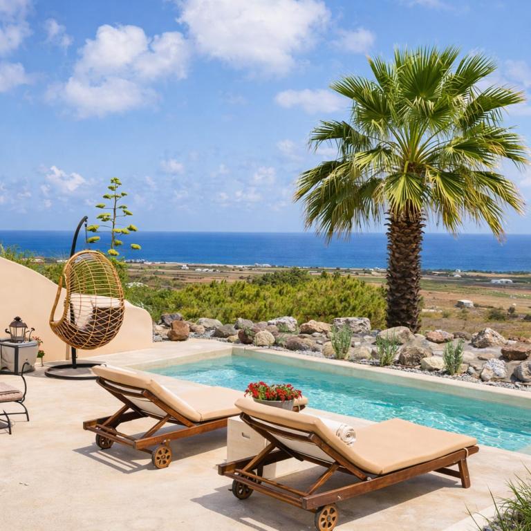 a pool with two lounge chairs and a palm tree at Pink Freud Villas Santorini in Oia