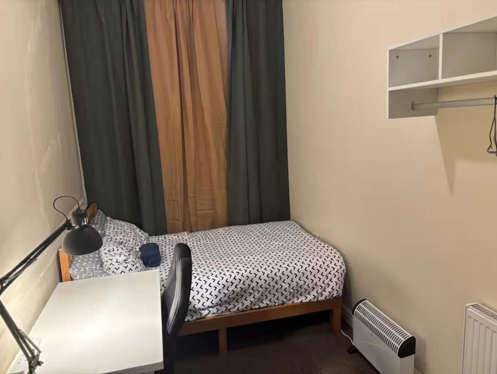a small room with a bed and a desk at Lubona Stirchley Guest House in Birmingham