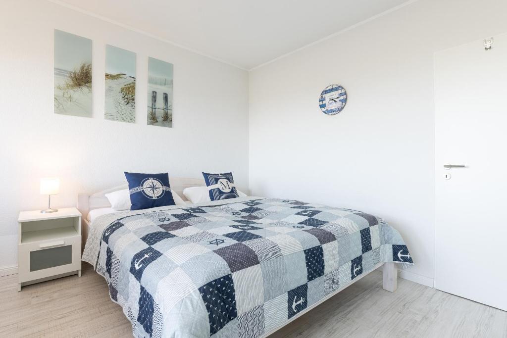 a bedroom with a bed with a blue and white blanket at Strandhaferweg 1 Utkiekerblick in Burgtiefe auf Fehmarn 