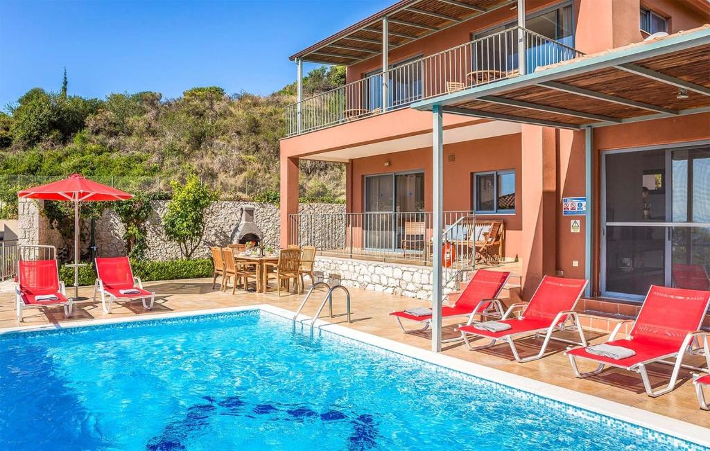 a swimming pool with red chairs and a house at Villa Giorgio by Villa Select in Kefallonia