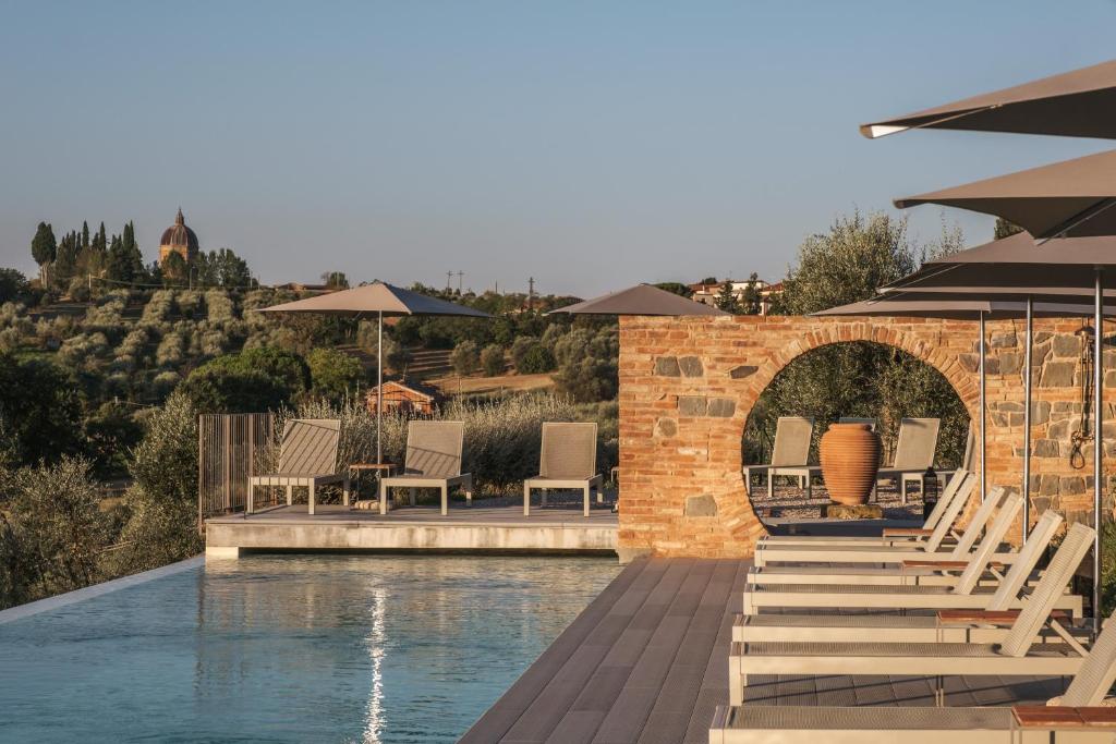ein Schwimmbecken mit Stühlen und Tischen und ein Schwimmbecken in der Unterkunft Borgo 69 Villas & Suites in Foiano della Chiana