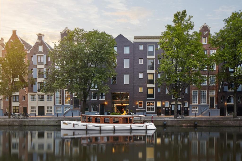 um barco na água em frente aos edifícios em Pulitzer Amsterdam em Amesterdão