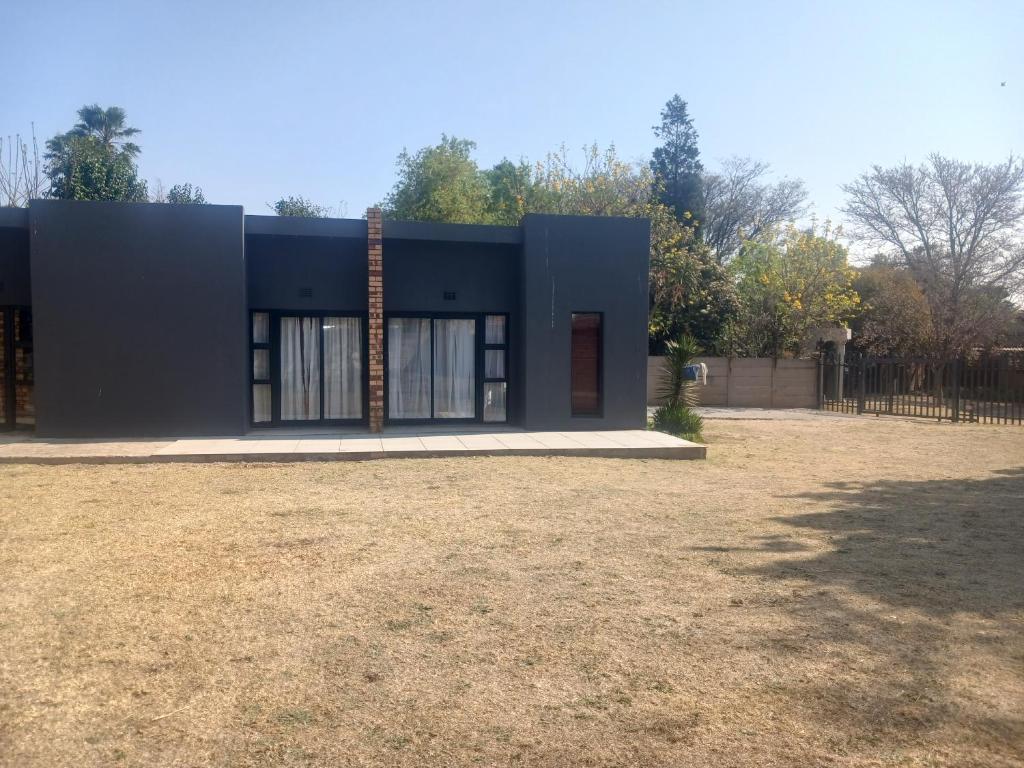 a black house in a field with a fence at Donido's Place in Alberton