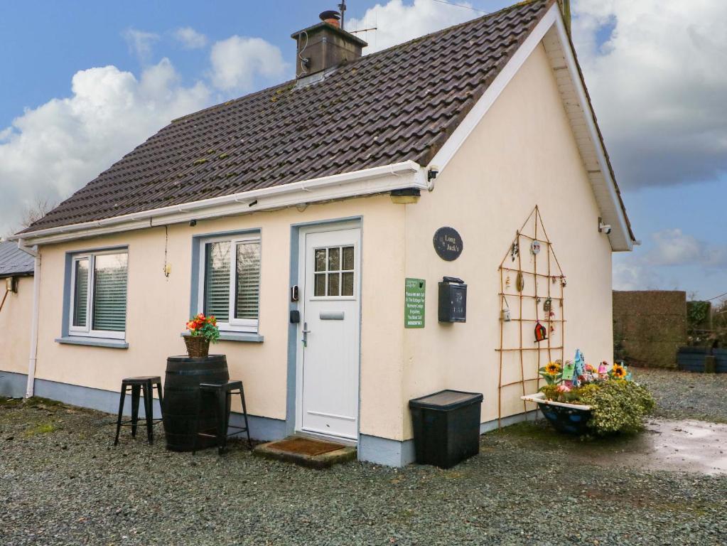 a small cottage with a white door and a window at Long Jack's in Ballygarrett