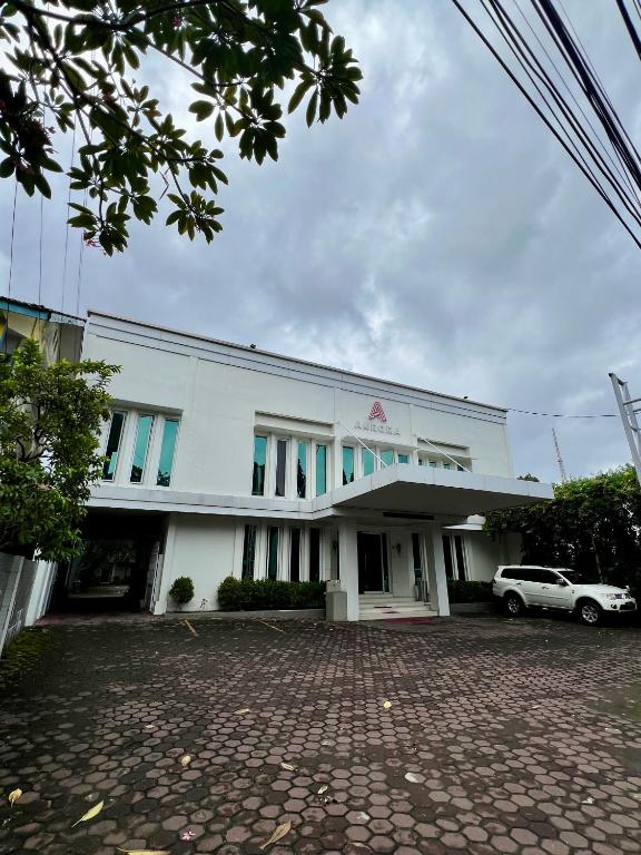 a white building with a car parked in front of it at Aurora Hotel Siliwangi in Cirebon