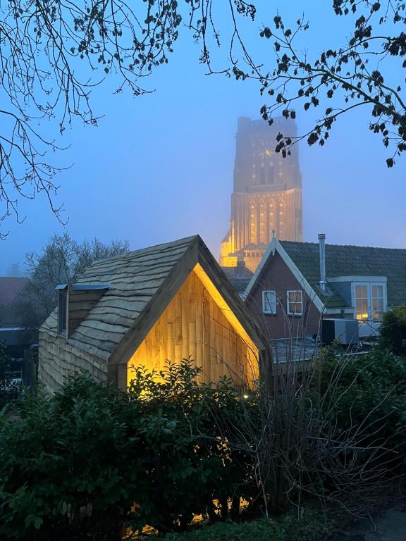 a wooden house with a building in the background at de KruidenPoort in Woudrichem