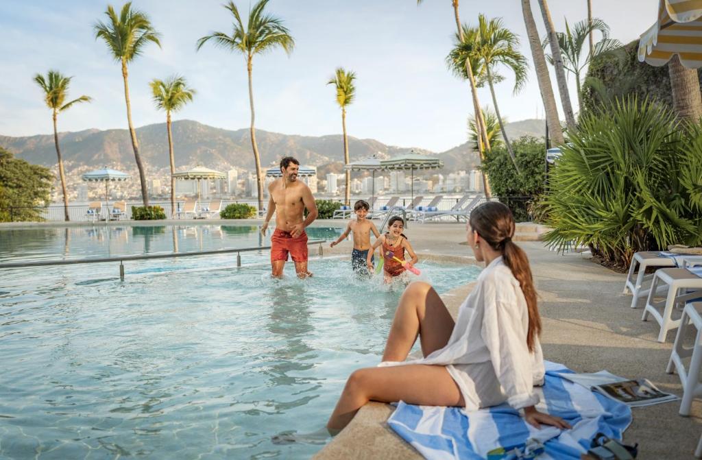 a family playing in the swimming pool at a resort at Park Royal Beach Acapulco - All Inclusive in Acapulco