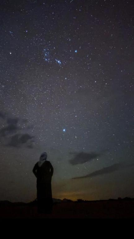 a man is looking up at the night sky at Silent Sands in Wadi Rum