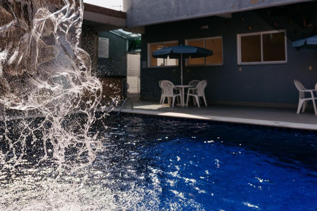 a water fountain in front of a swimming pool at Hotel Santamaria in Guarujá
