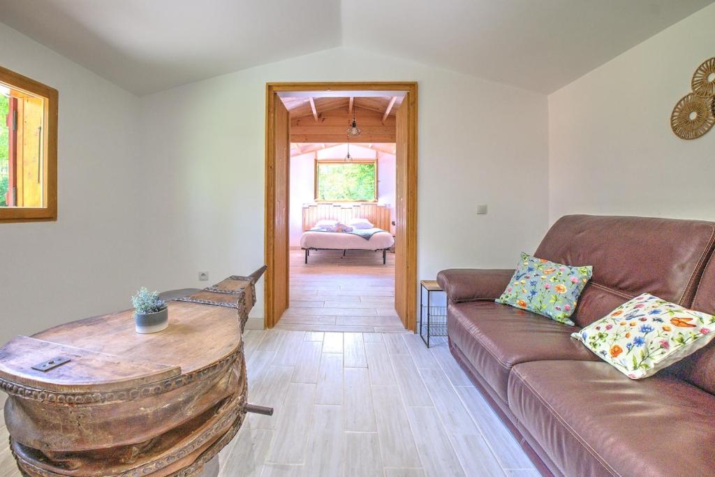 a living room with a couch and a wooden table at Le chalet sur Manoire in Saint-Laurent-sur-Manoire
