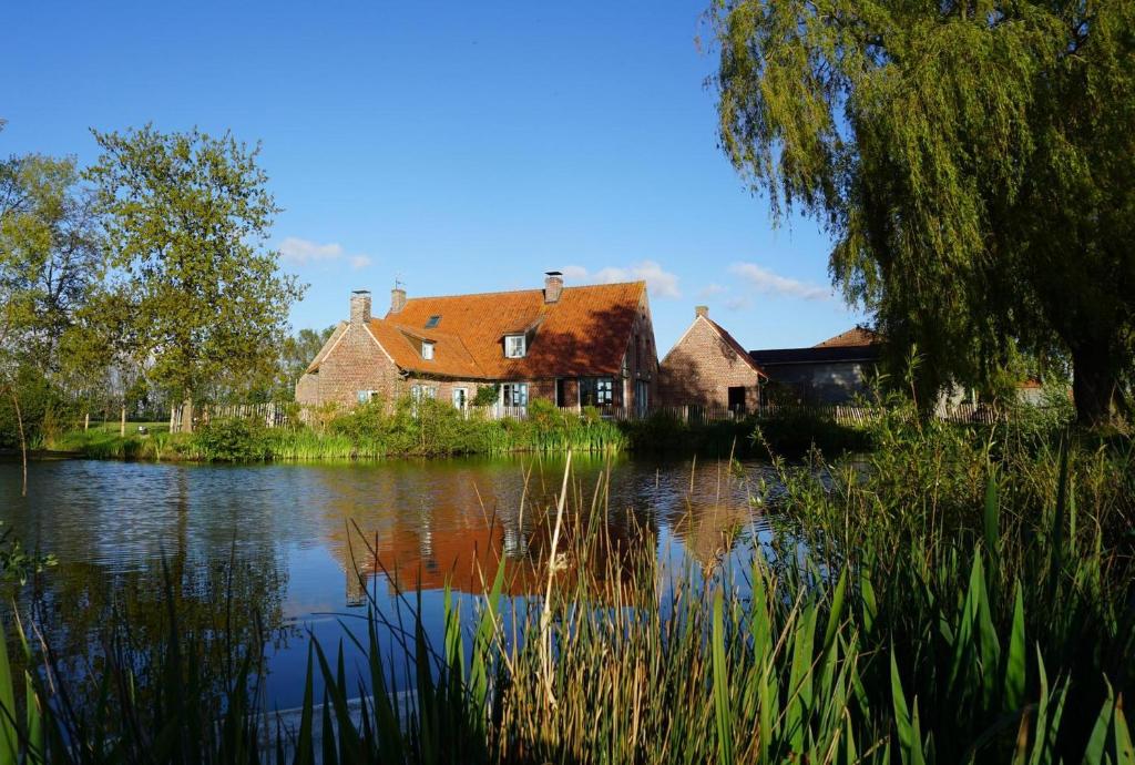 a house next to a river with a house at La Ferme de Beauvoorde - 13 personnes in Steenvoorde