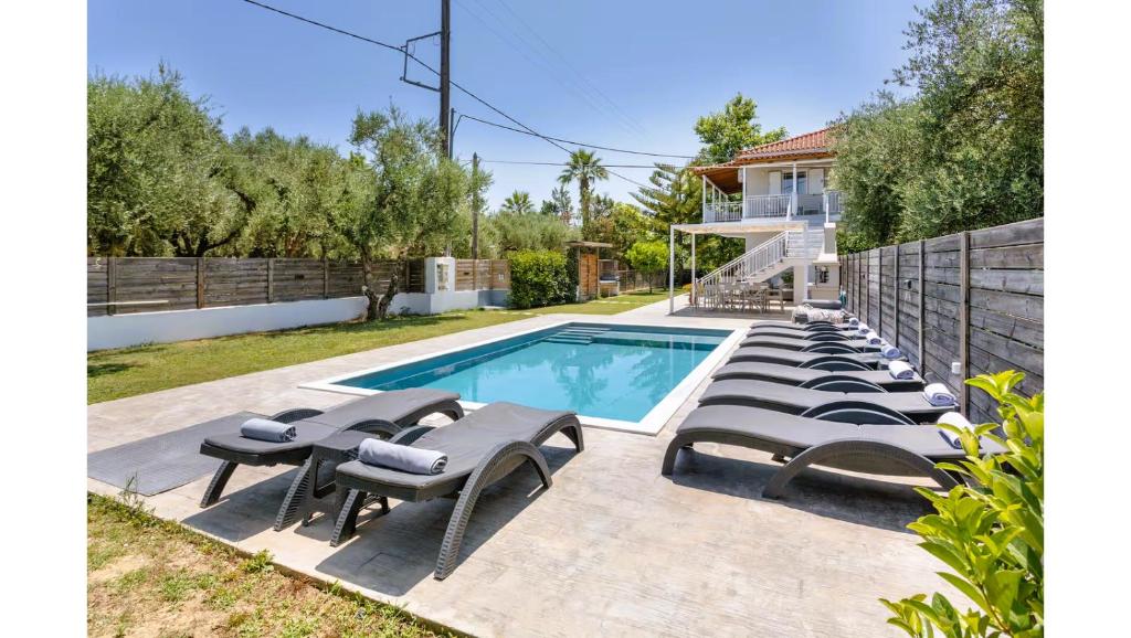 a swimming pool with lounge chairs next to a house at Ruvelis private pool villa in Fiolítis