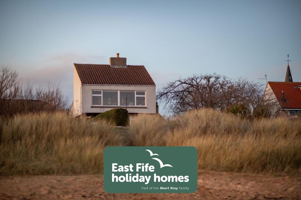 a house in a field with a sign in front of it at East Vows - Elie in Earlsferry