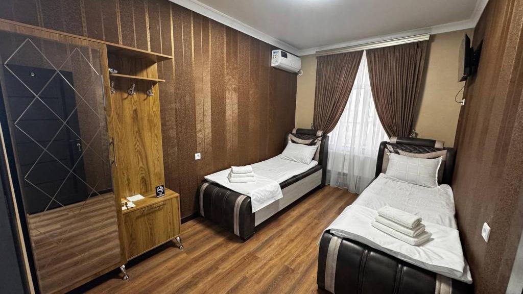 a small room with two beds and a window at Over City Hostel in Margilan