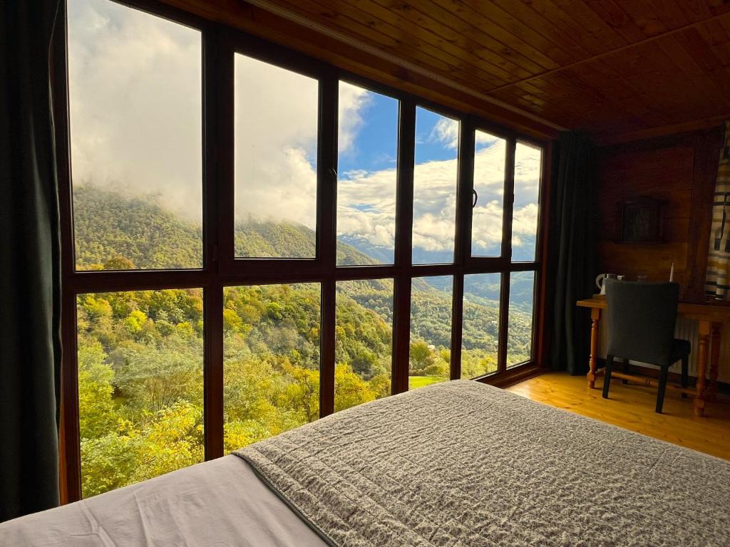 a bedroom with a large window with a view of the mountains at Gentry House in Ambrolauri