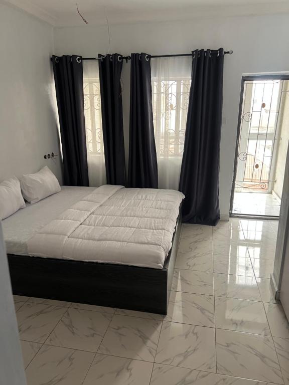 a bedroom with a bed with black curtains and a window at Otijoe Premier Hotel 2 in Port Harcourt