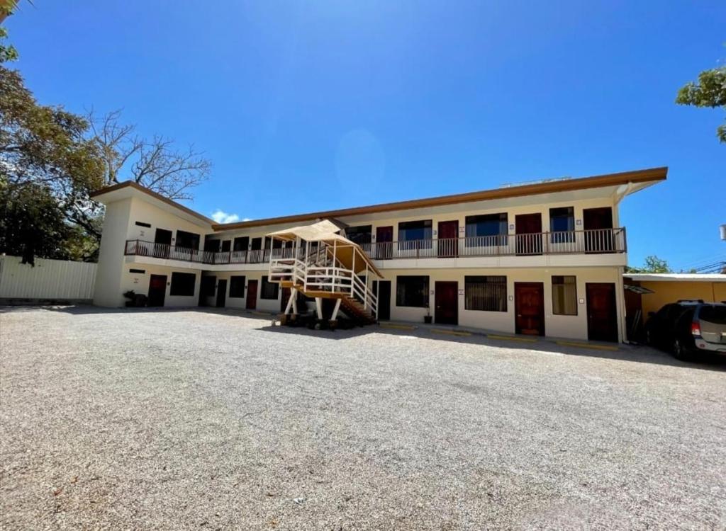a large white building with a balcony and a parking lot at Hotel Wilson Condega in Liberia