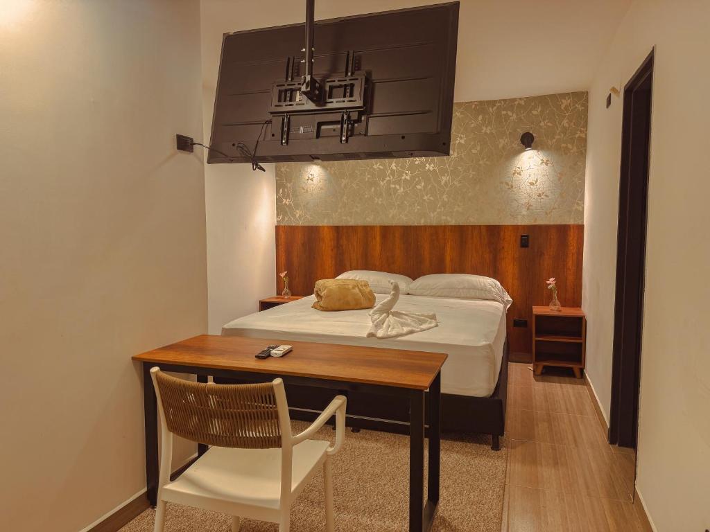a bedroom with a bed and a table and a desk at Apartaestudios Zeni in Medellín
