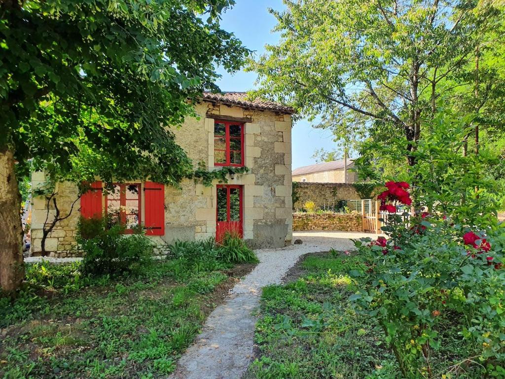 a stone house with red doors and a driveway at Gîte de Marcoux, authentic and warme house in Saint-Laon