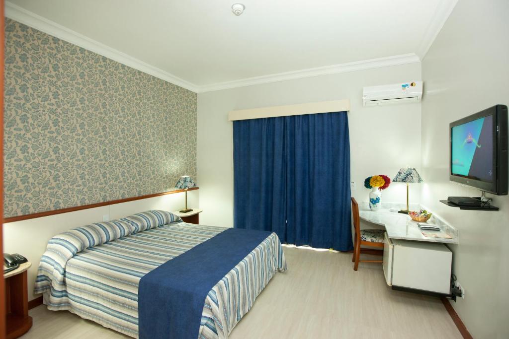 a hotel room with a bed and a desk and a television at Hotel Colonial Plaza in Itu