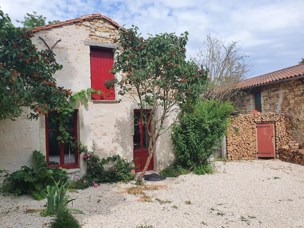a stone house with red windows and a tree at Maisonette, Gîte de la Mère Nini in Saint-Laon