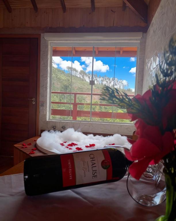 a bottle of wine sitting on a table next to a window at Pousada Varanda Colibri in Monte Verde