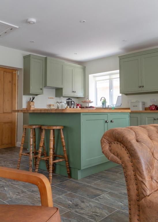 a kitchen with green cabinets and two stools in it at Stanton Lodge Cottage - 2 bedrooms - sleeps 5 in Curbar