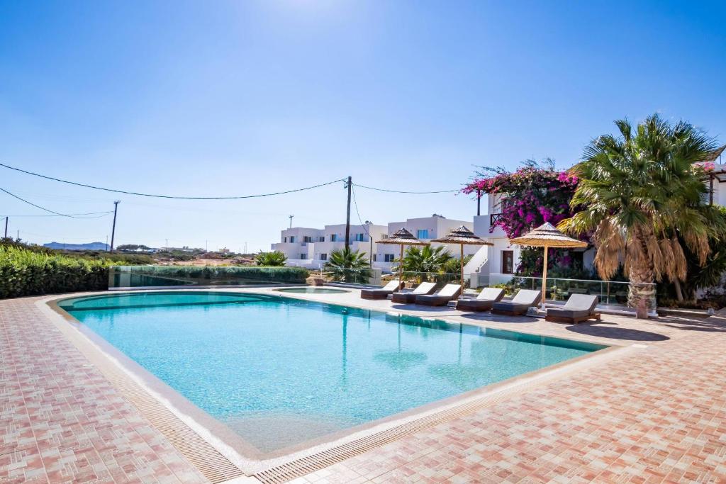 een groot zwembad met ligstoelen en een parasol bij Punta Mare Hotel in Karpathos