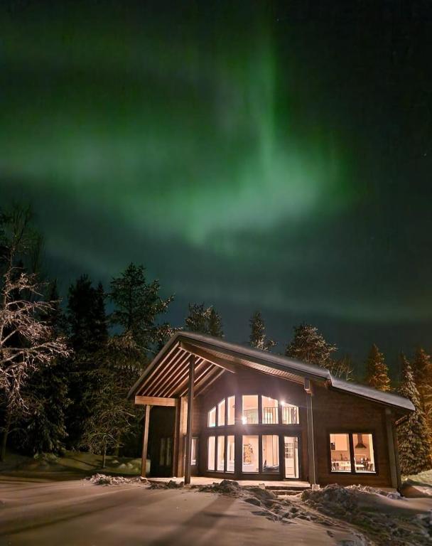 a house with the green northern lights in the sky at Villa Vaellus in Ruka