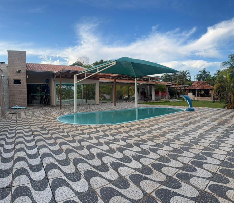 a swimming pool with a green umbrella and a house at Pousada Coxim in Coxim