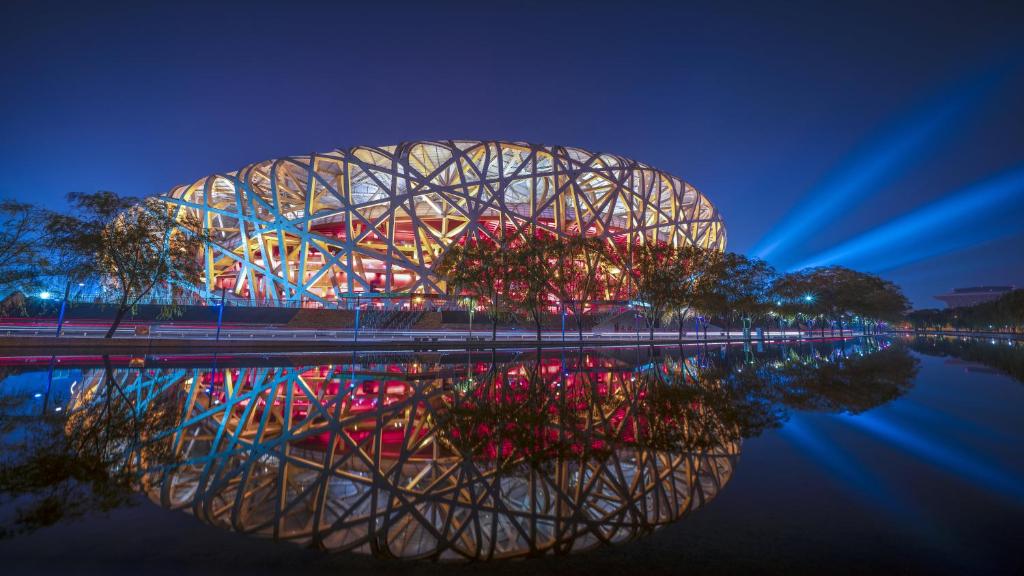 ein Gebäude, das sich nachts im Wasser spiegelt in der Unterkunft InterContinental Beijing Beichen by IHG in Peking