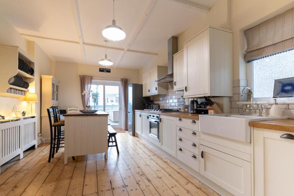 a kitchen with white cabinets and a wooden floor at 3 Bed in Mumbles oc-hh1223 in The Mumbles