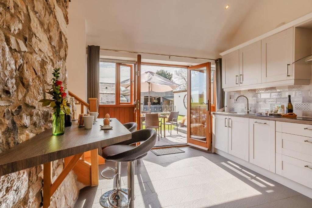 a kitchen with white cabinets and a stone wall at 2 Bed in Lixwm oc-bow179 in Halkyn