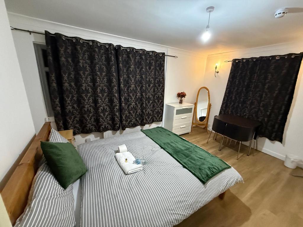 a bedroom with a bed with two green pillows at Exquisite King-sized Bedroom - Free Parking in Dartford