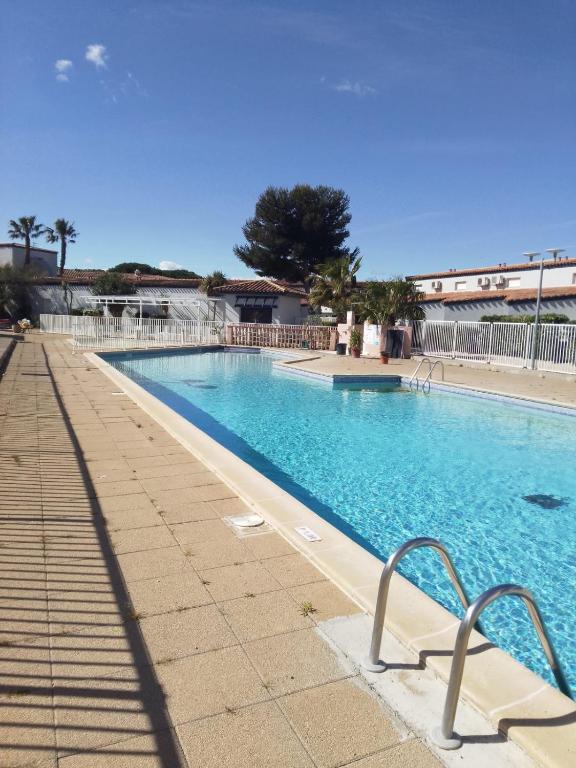a large blue swimming pool with a bench next to it at RESIDENCE du NEPTUNE in Saint-Cyprien-Plage