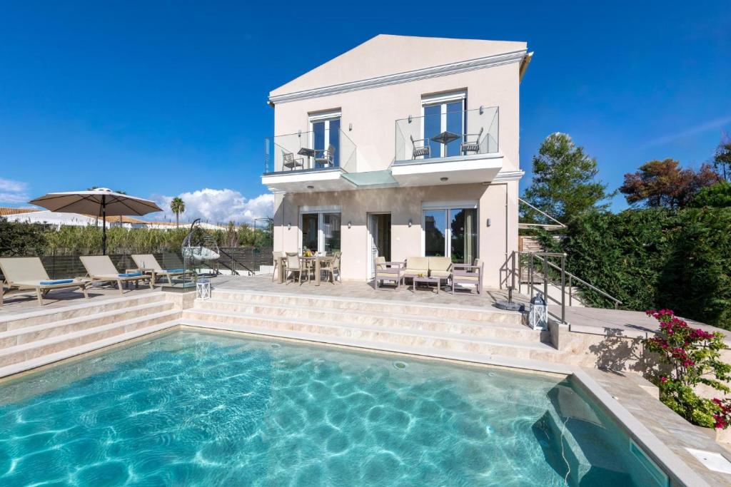 a villa with a swimming pool in front of a house at Thalia by Vintage Travel in Agios Georgios