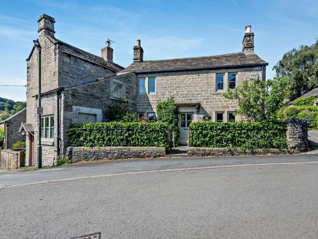 an old stone house on the side of a street at 4 Bed in Hope Valley oc-pk939 in Curbar