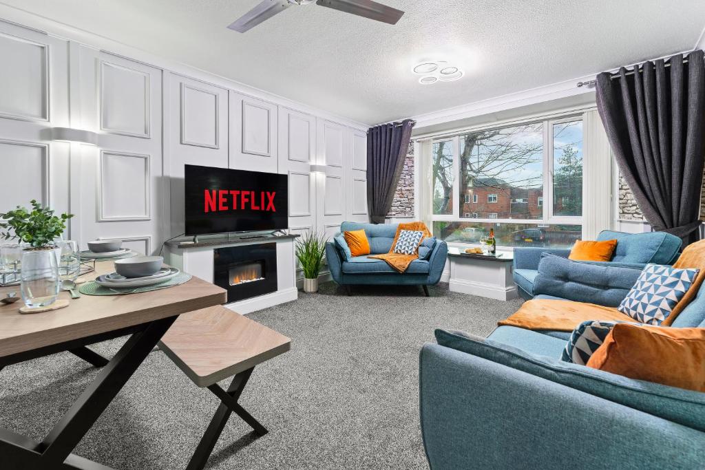 a living room with blue furniture and a tv at Churchill Apartment- 4 Beds- Free Parking- Near NEC BHX & HS2 in Coleshill