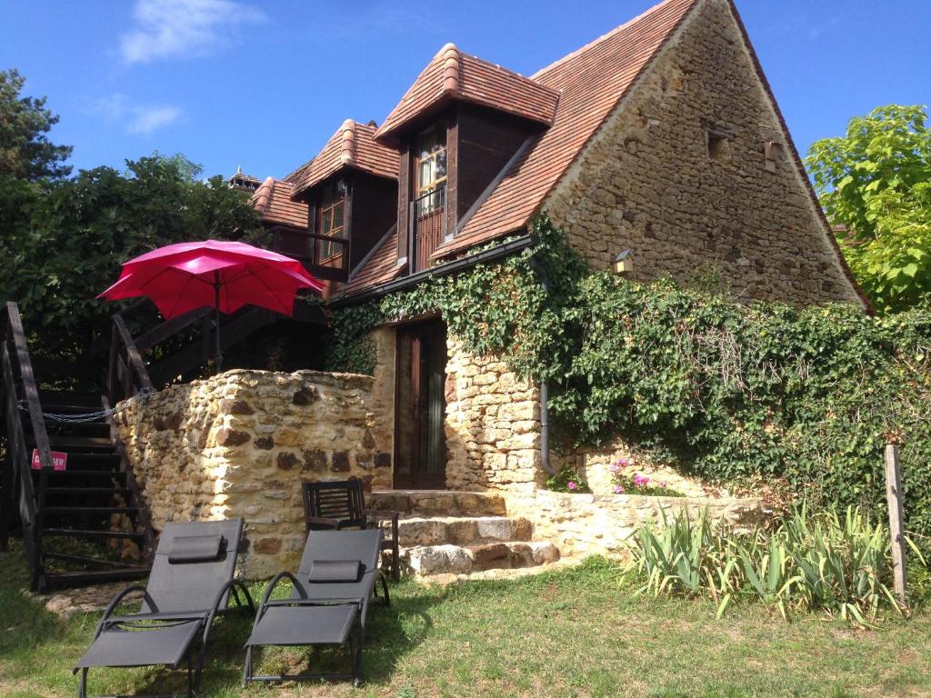 a house with chairs and an umbrella in front of it at Lo Petit Cretsou in Simeyrols