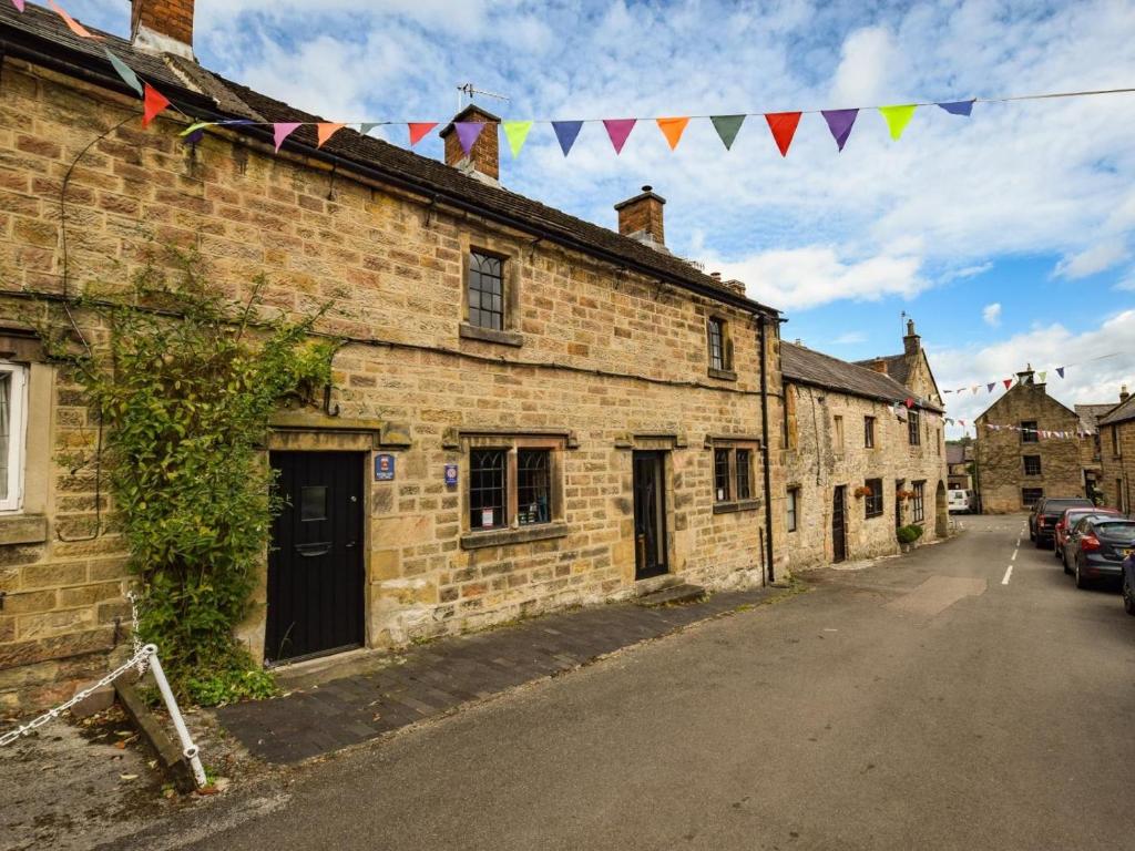 an old brick building with flags on a street at 2 Bed in Matlock oc-pk885 in Winster