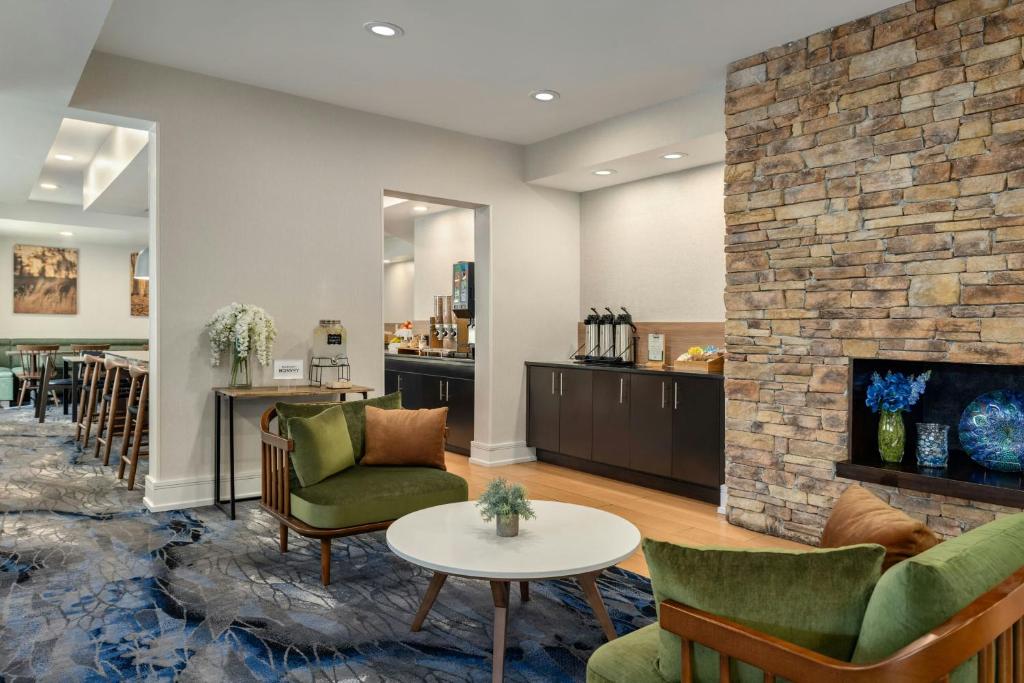 a lobby with a fireplace and chairs and a table at Fairfield Inn & Suites Savannah I-95 South in Savannah