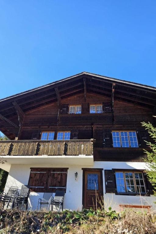 a large wooden house with chairs in front of it at Apartment Châlet Hochmatt by Interhome in Im Fang