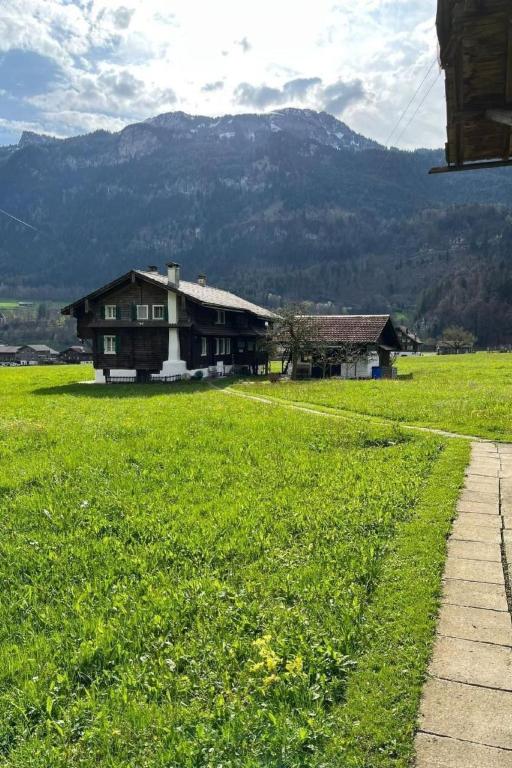 a house in a field of grass with mountains in the background at Apartment Lungern by Interhome in Lungern