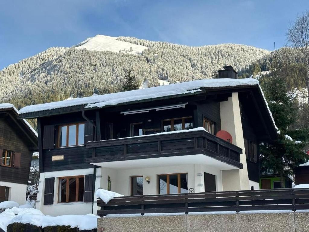 a house covered in snow with a mountain in the background at Apartment Rothornblick by Interhome in Sörenberg