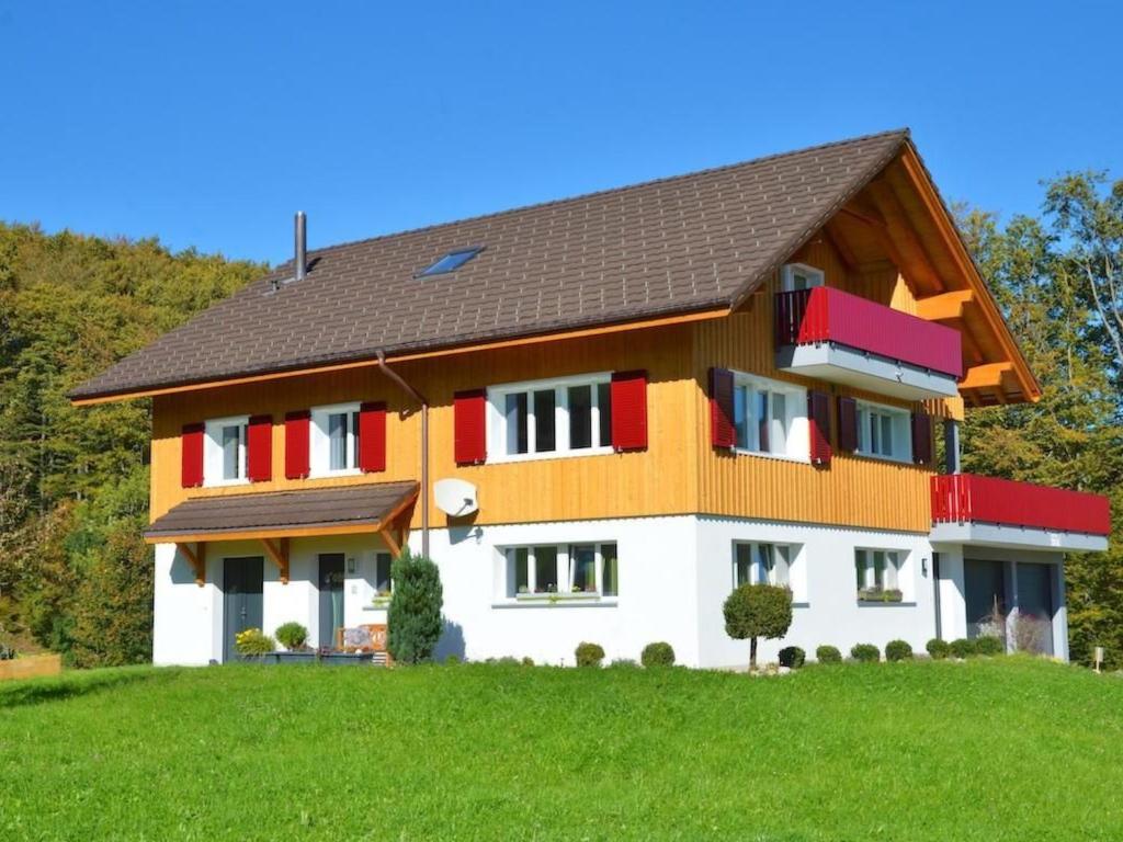 a house with red and white trim on a green hill at Apartment S'Ottä by Interhome in Sattel