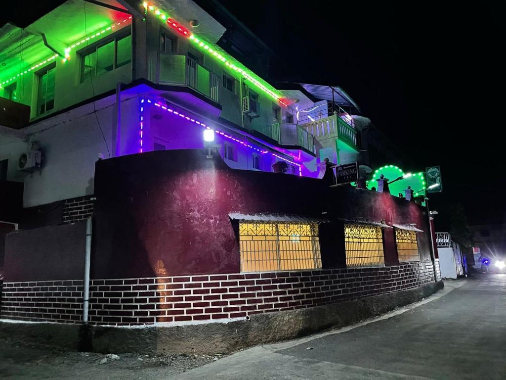 a building with colorful lights on the side of it at Hôtel Restaurant Le Papillon in Goungouamoué